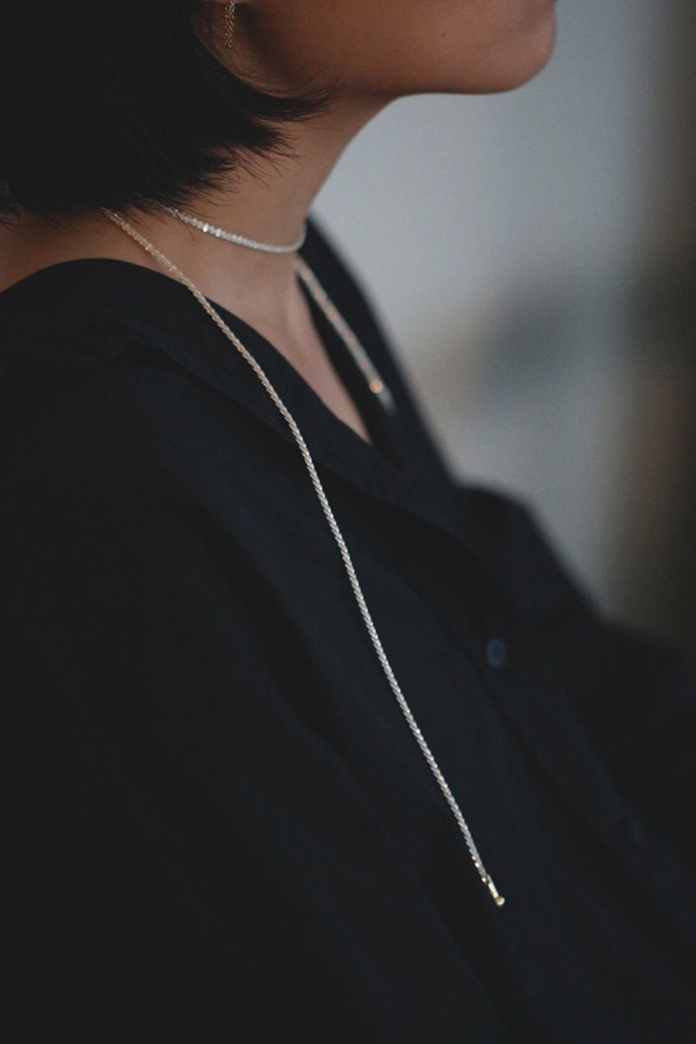 Layered Silver Necklaces Glowing Against Dark V-Neck | Seysage