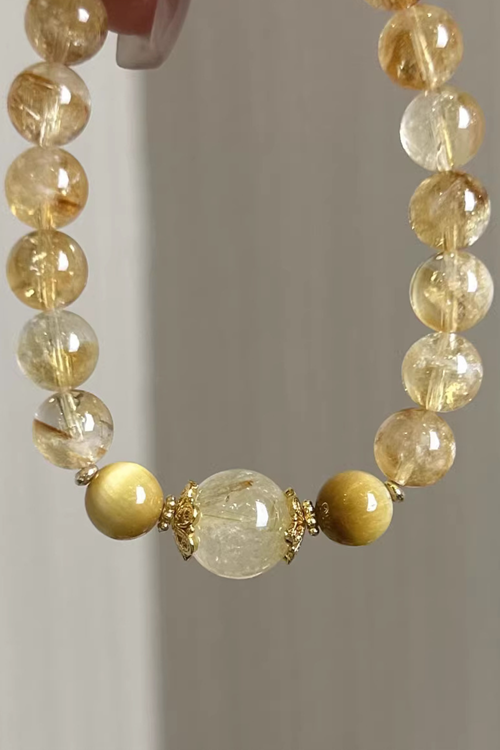 Close-up of golden rutile strands in quartz beads - Neutral gray background​