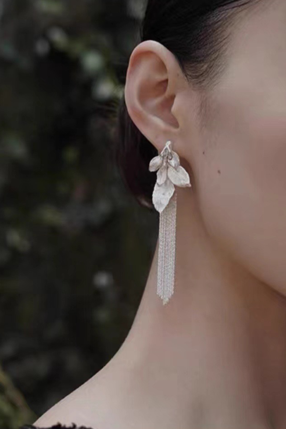 Close-up: Silver leaf chains against emerald foliage background - Botanical art jewelry
