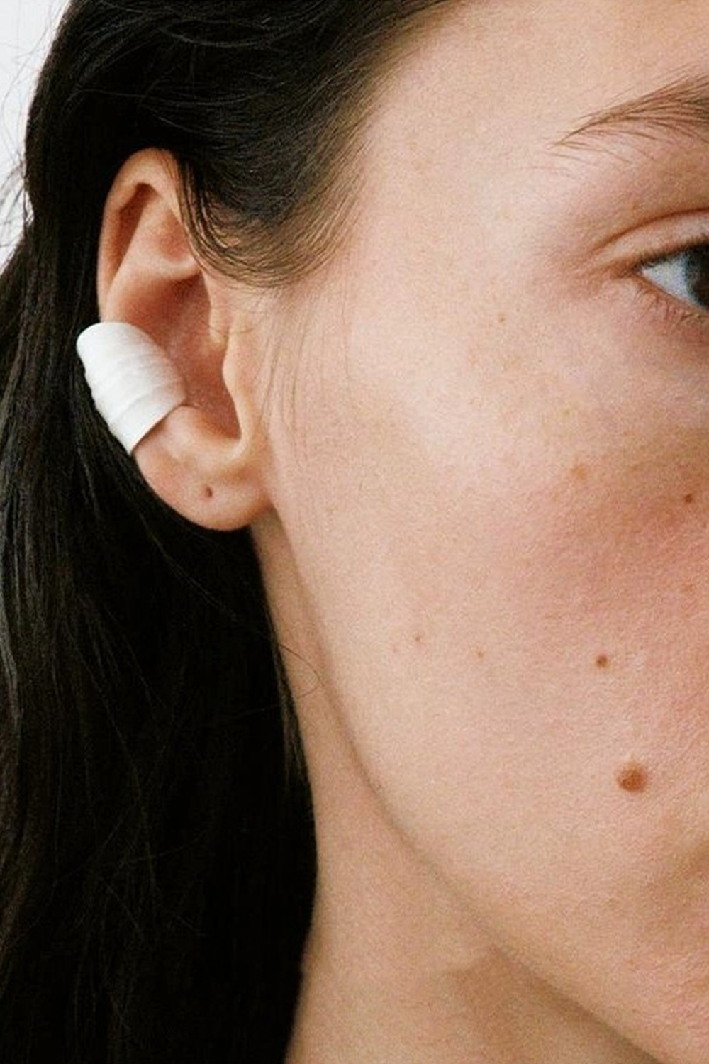 Long-haired woman wearing wave ear cuff - Black ponytail focus with white background