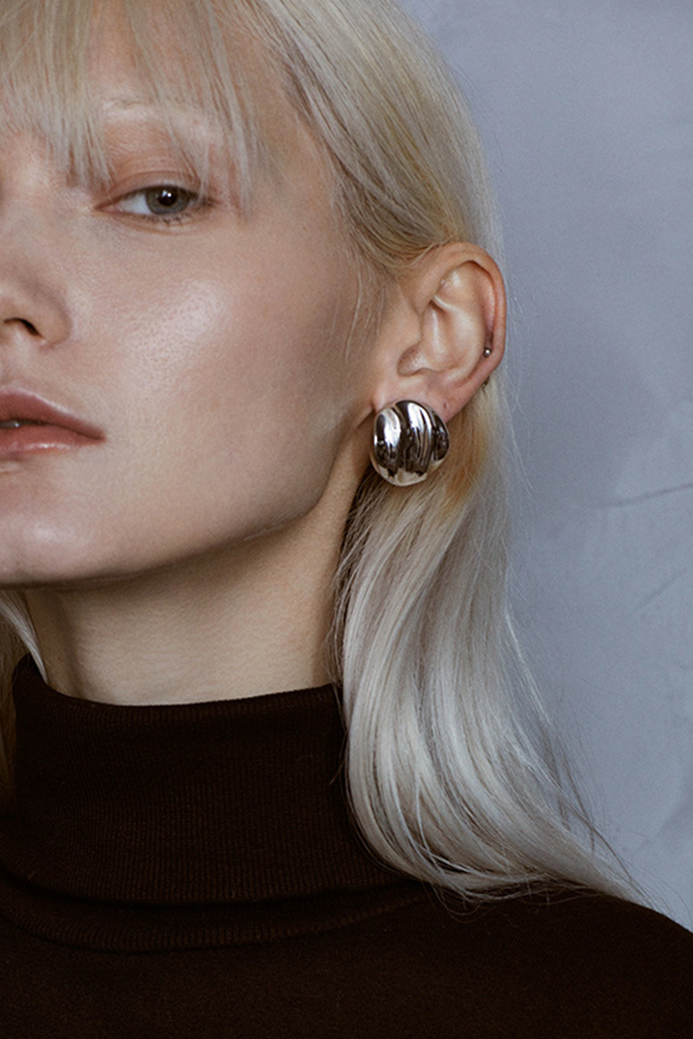 Silver Textured Circle Studs Illuminating Fair Skin Against Grey | Seysage